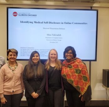 Mina and four of her committee members in front of her slideshow after her defense
                  